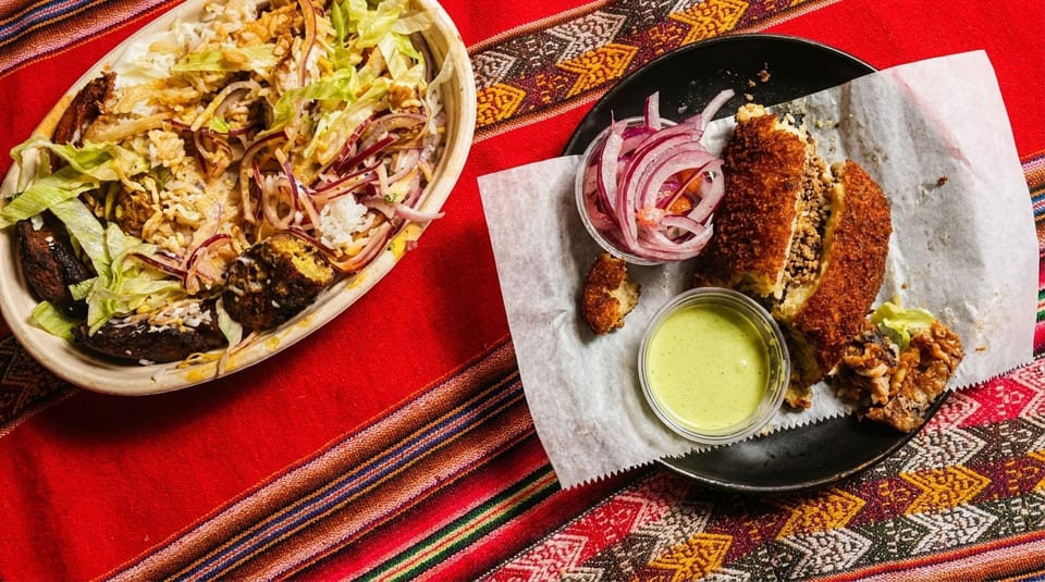 Peruvian food on a colorful striped tablecloth, featuring a rice bowl and a fried stuffed potato.