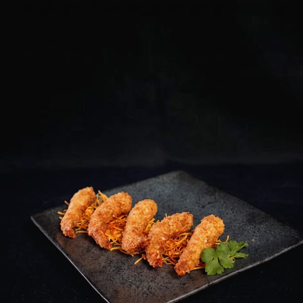 Five crispy fried shrimp on a bed of shredded carrots with a sprig of cilantro.